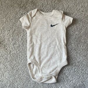 A beige Nike onesie for six months badys